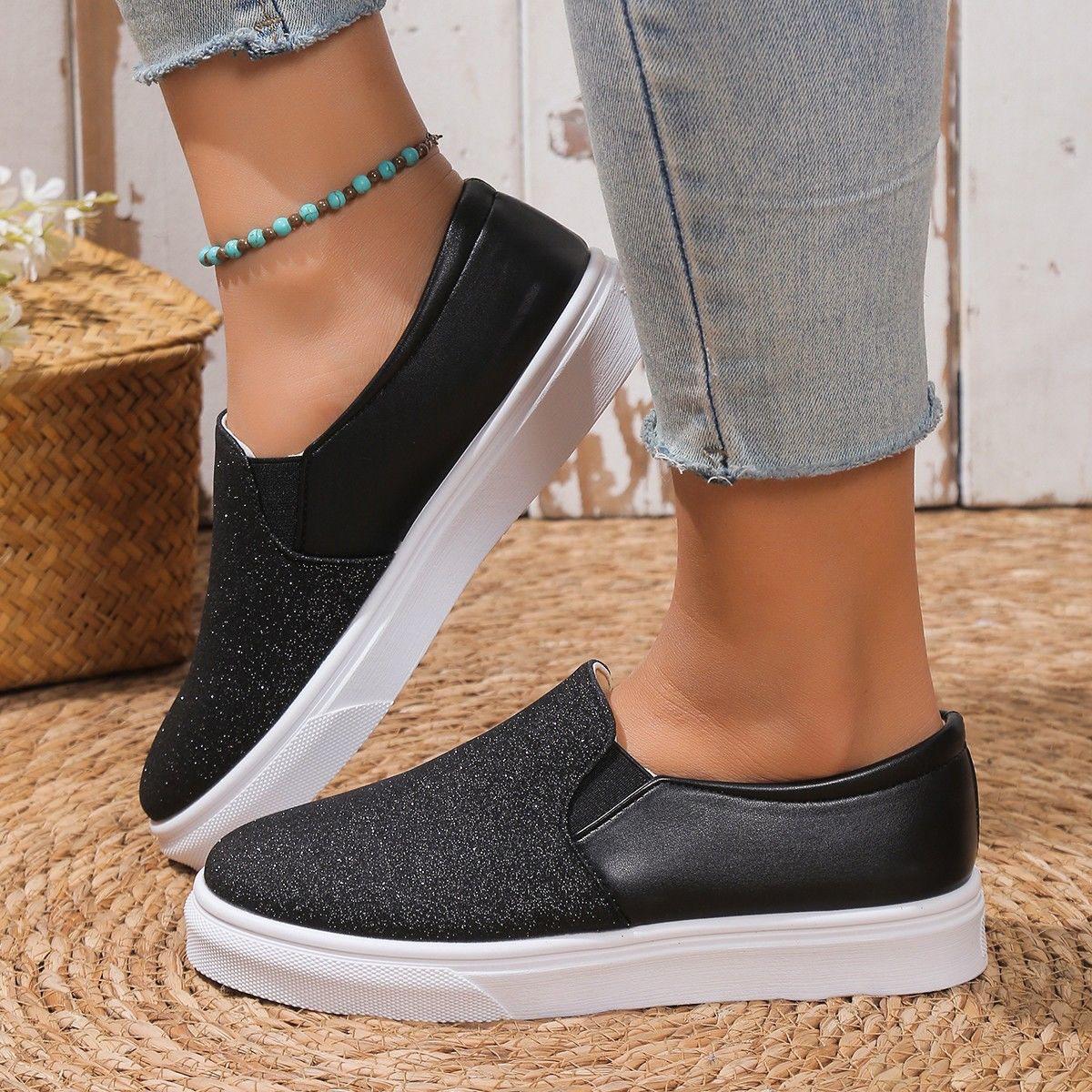 Front angle view of women's black shimmer slip-on sneakers showing elastic side gores and cushioned collar