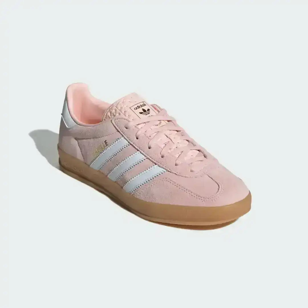 Fashionable Adidas Gazelle Indoor footwear in pastel pink suede, perfect for a casual retro look with its vintage-inspired gum sole and iconic white three stripes.