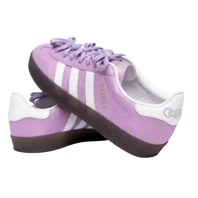 Adidas Gazelle Indoor Hello Kitty sneakers in a soft lilac purple colorway, featuring unique bow-shaped laces, white serrated stripes, and an all-over embossed bow pattern on the leather upper.