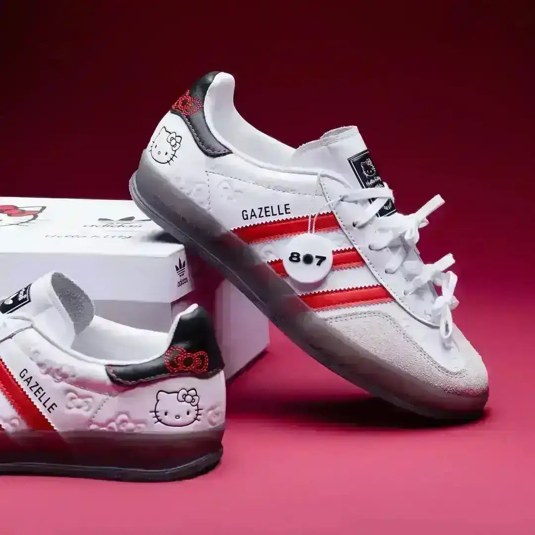 Limited Edition Adidas Gazelle Indoor Hello Kitty White/Red shoes featuring grey suede overlays, red serrated stripes, and a unique black heel tab with a red bow graphic and face detail.