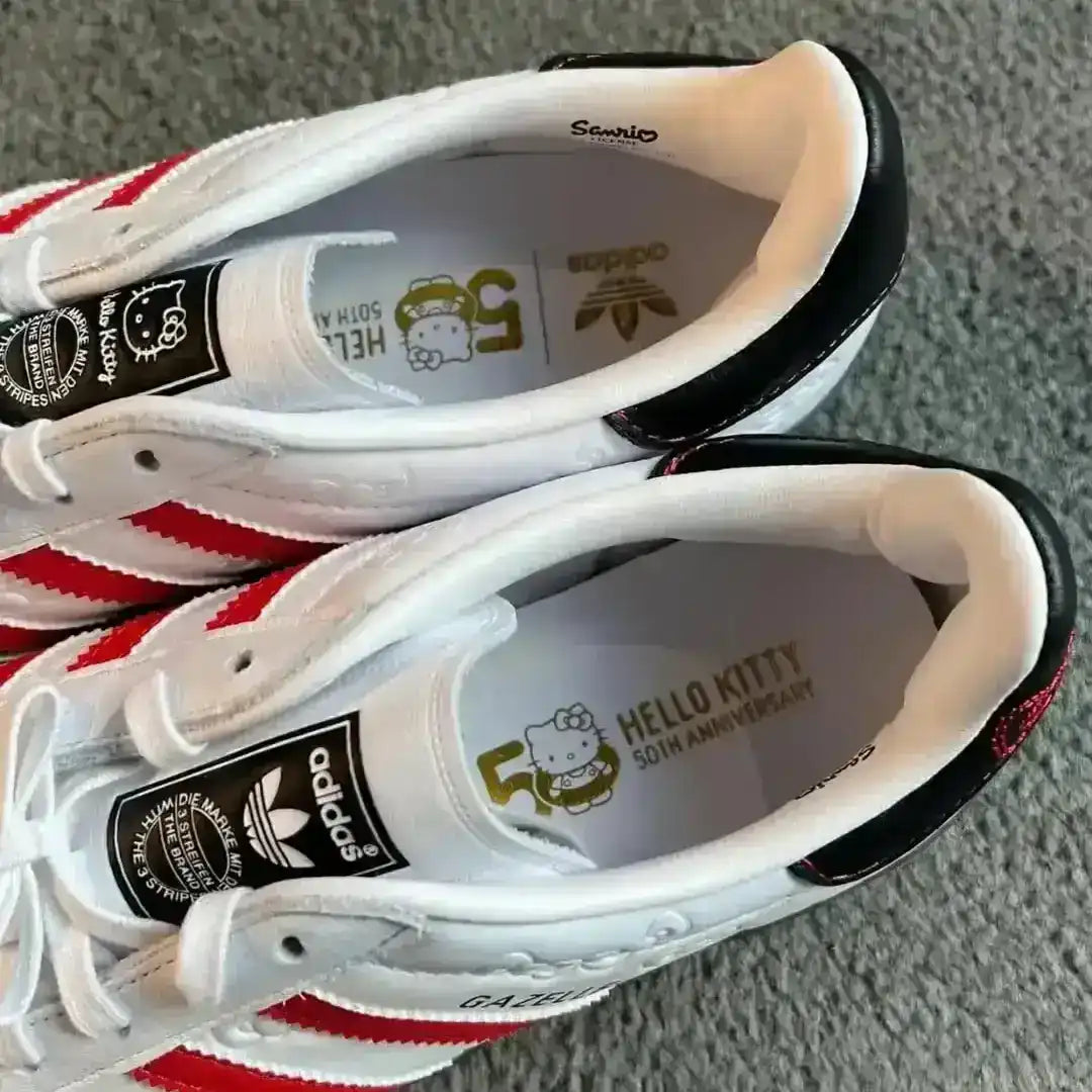 Adidas Gazelle Indoor Hello Kitty collaboration model in white leather with red stripes, featuring a grey suede toe, black heel tab details, and Sanrio character branding for a cute aesthetic.