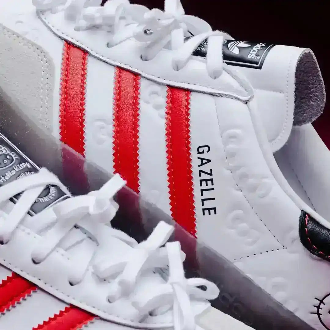 Detailed look at the Adidas Gazelle Indoor Hello Kitty White Red sneakers, showing the textured leather upper with bows, red side stripes, and the iconic Hello Kitty face near the ankle collar.
