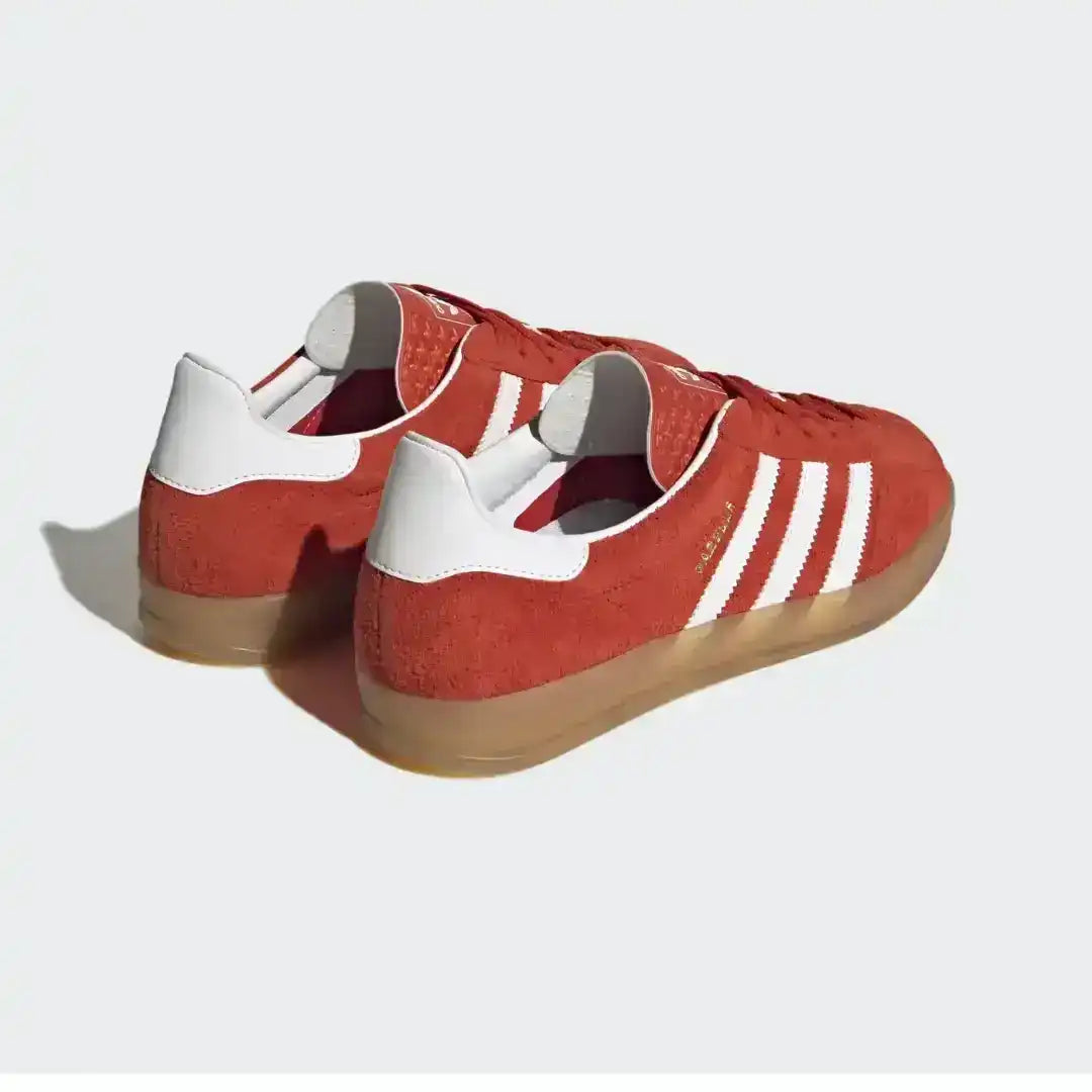 Adidas Gazelle Indoor trainers in red and white, highlighted by a lush suede construction, white leather heel tab, and a semi-transparent gum outsole for vintage style.