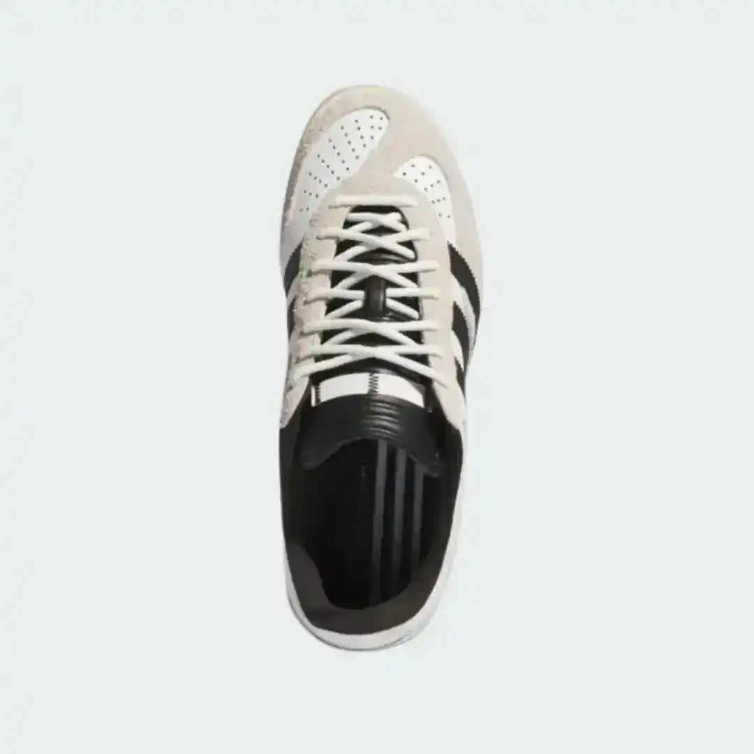 Minimalist Adidas Gazelle Indoor kicks in white and black, featuring a low-profile silhouette, gum sole traction, and premium leather construction suitable for daily wear.