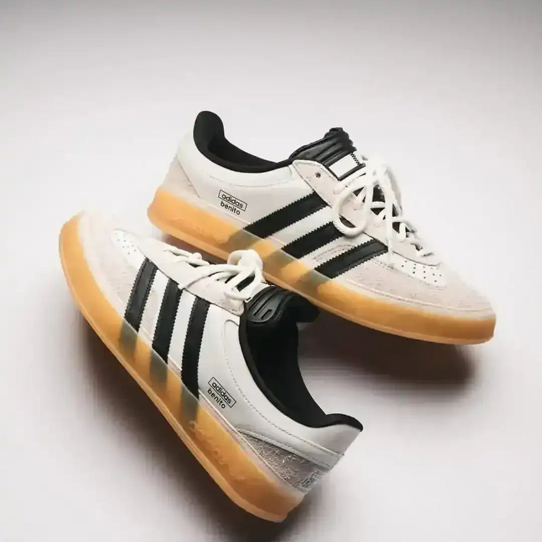 Studio shot of the Adidas Gazelle Indoor in White/Black/Gum, showcasing the lateral side details including the serrated stripes, suede overlays, and textured leather tongue.