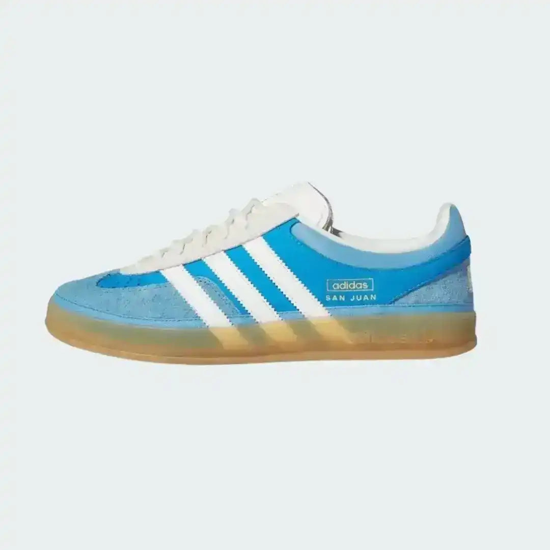 Blue and white Adidas sneaker with a gradient sole on a light gray background
