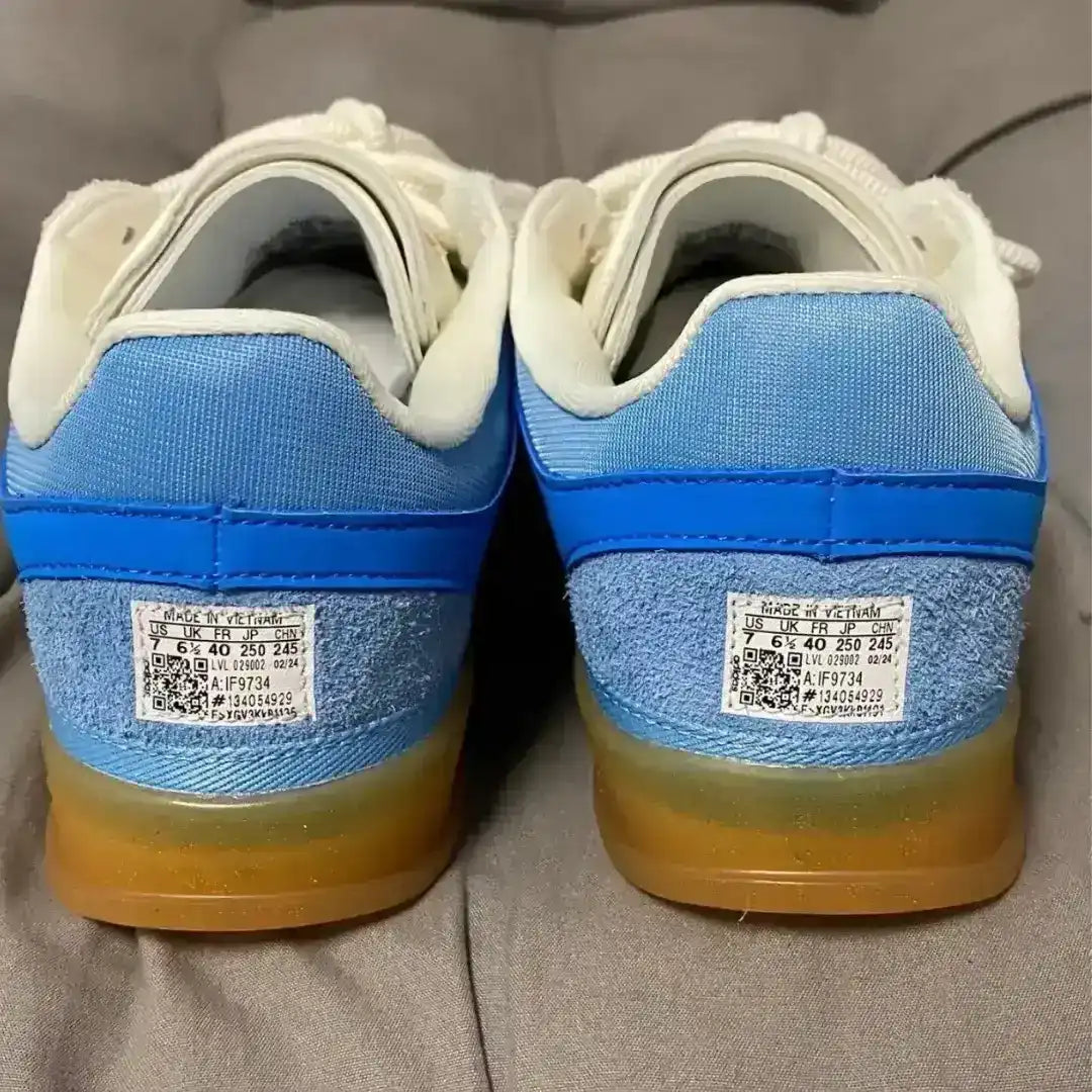 Pair of blue and white sneakers with visible brand labels on a gray surface