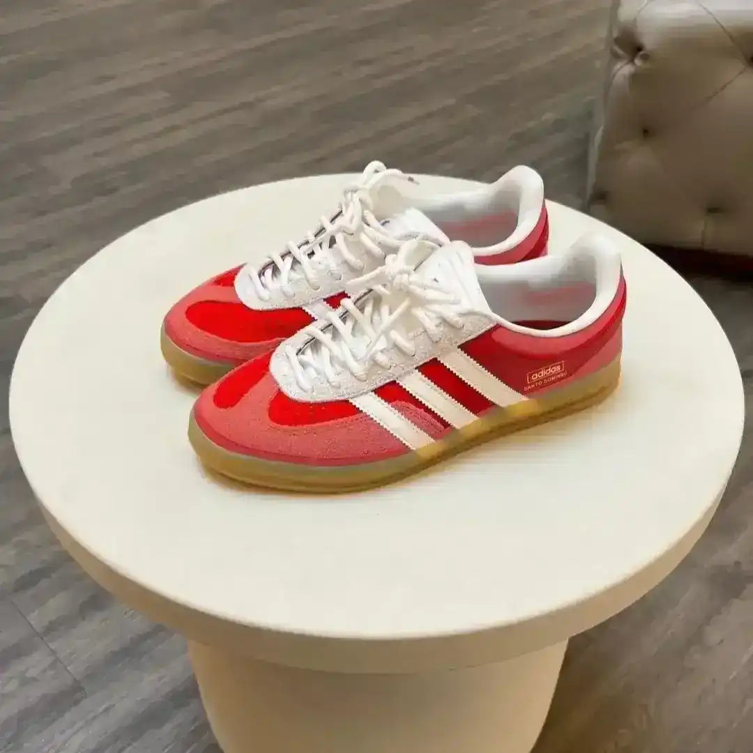 Red and white sneakers with three stripes on a small round table.