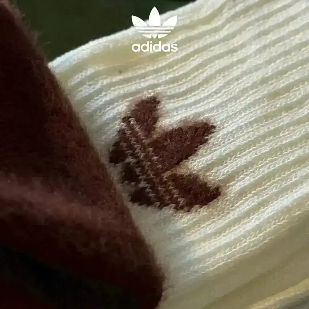 Essential Adidas cozy socks for cold weather, made from a fluffy knit fabric and featuring the classic Trefoil logo in black, white, and brown color variations.