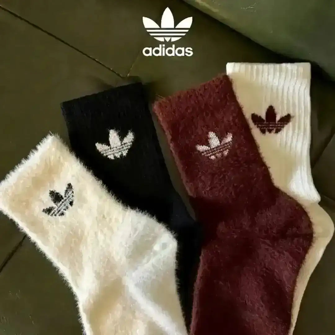 Adidas fuzzy socks in assorted colors including black and white, focusing on the plush knit material and the distinct logo details.