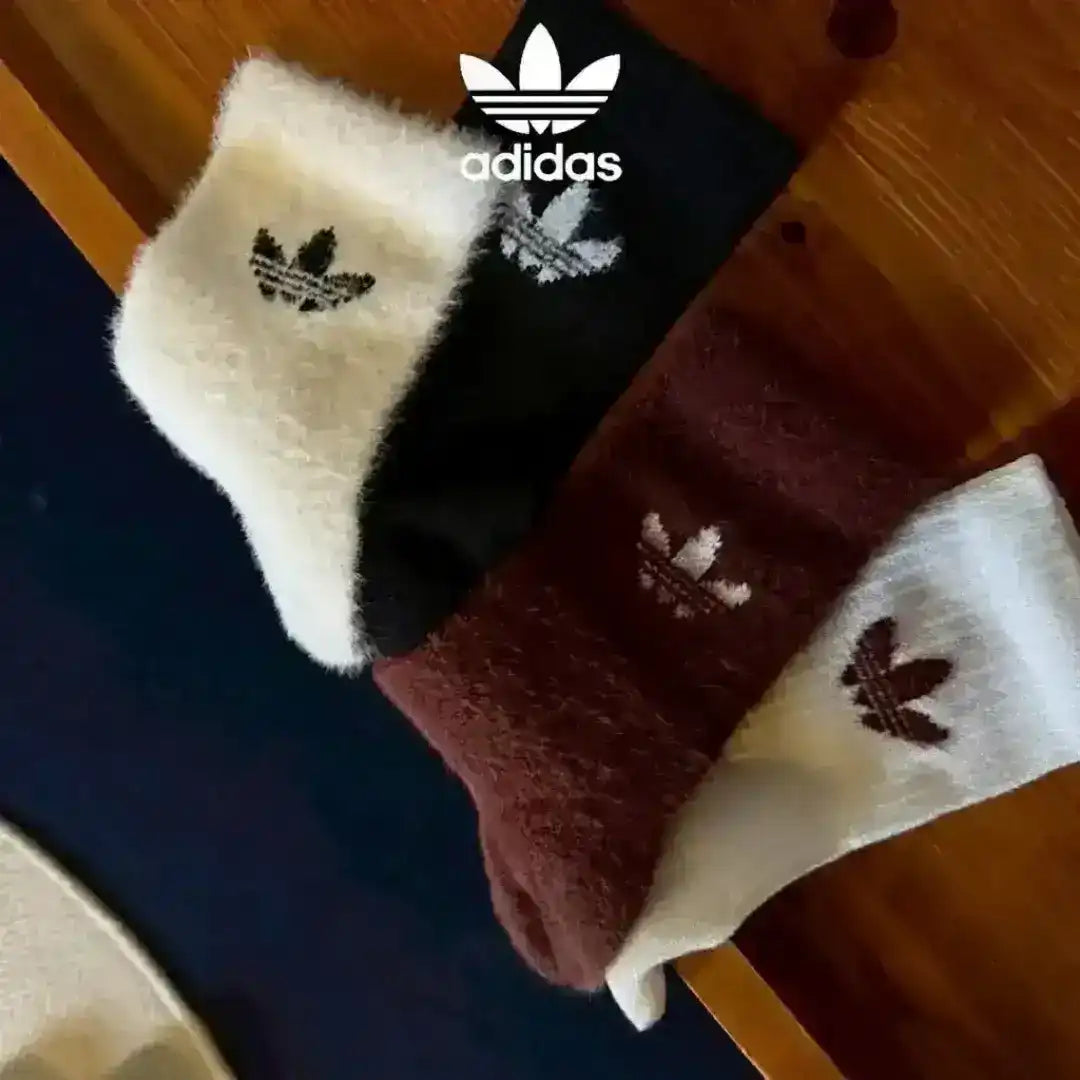 Close-up of Adidas Originals cozy socks in contrasting colors like black and white, highlighting the super soft fuzzy finish and embroidered branding details.