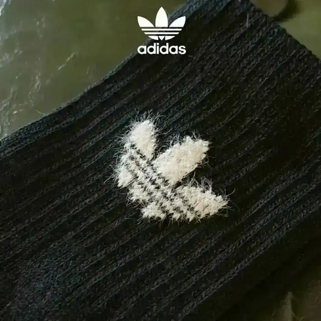 Adidas winter socks with a thick, fuzzy texture designed for maximum comfort, showing the Trefoil logo clearly on the black and white versions in the display.