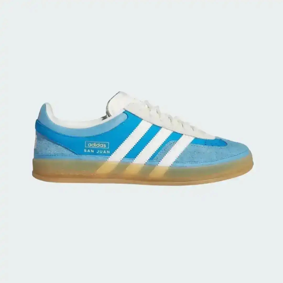 Blue Adidas sneaker with white stripes on a light gray background