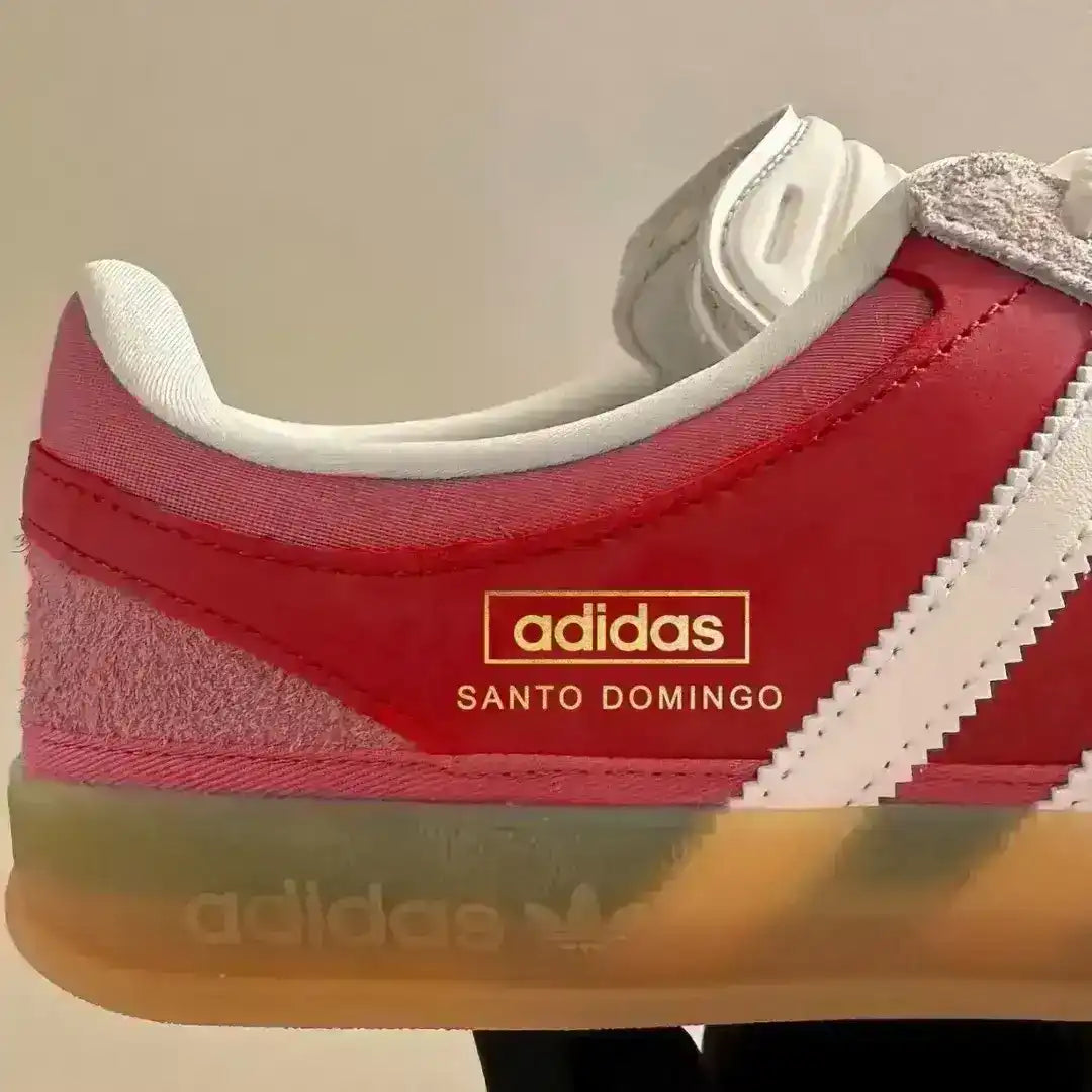Red and pink Adidas sneaker with 'Santo Domingo' text on a beige background