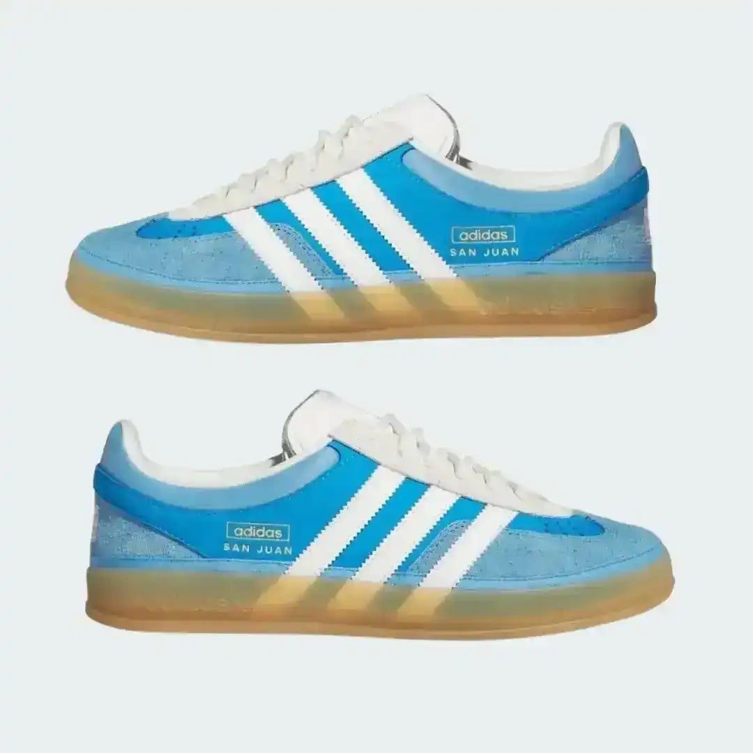 Pair of blue and white Adidas sneakers with a gradient sole on a light gray background