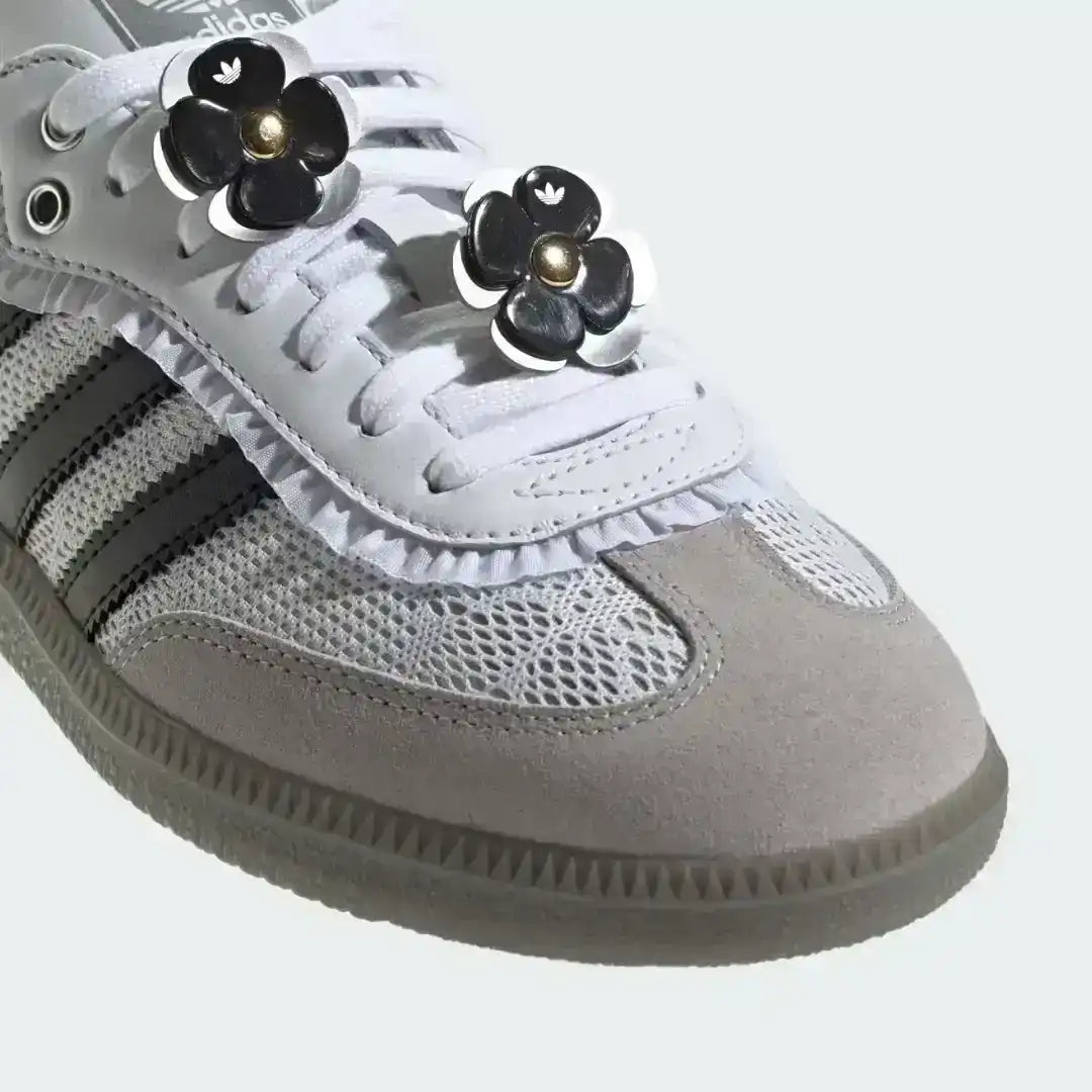 Custom Adidas Samba OG shoes in white, featuring a grey suede toe cap, black serrated stripes, and unique black and white striped ribbon lacing with floral details.