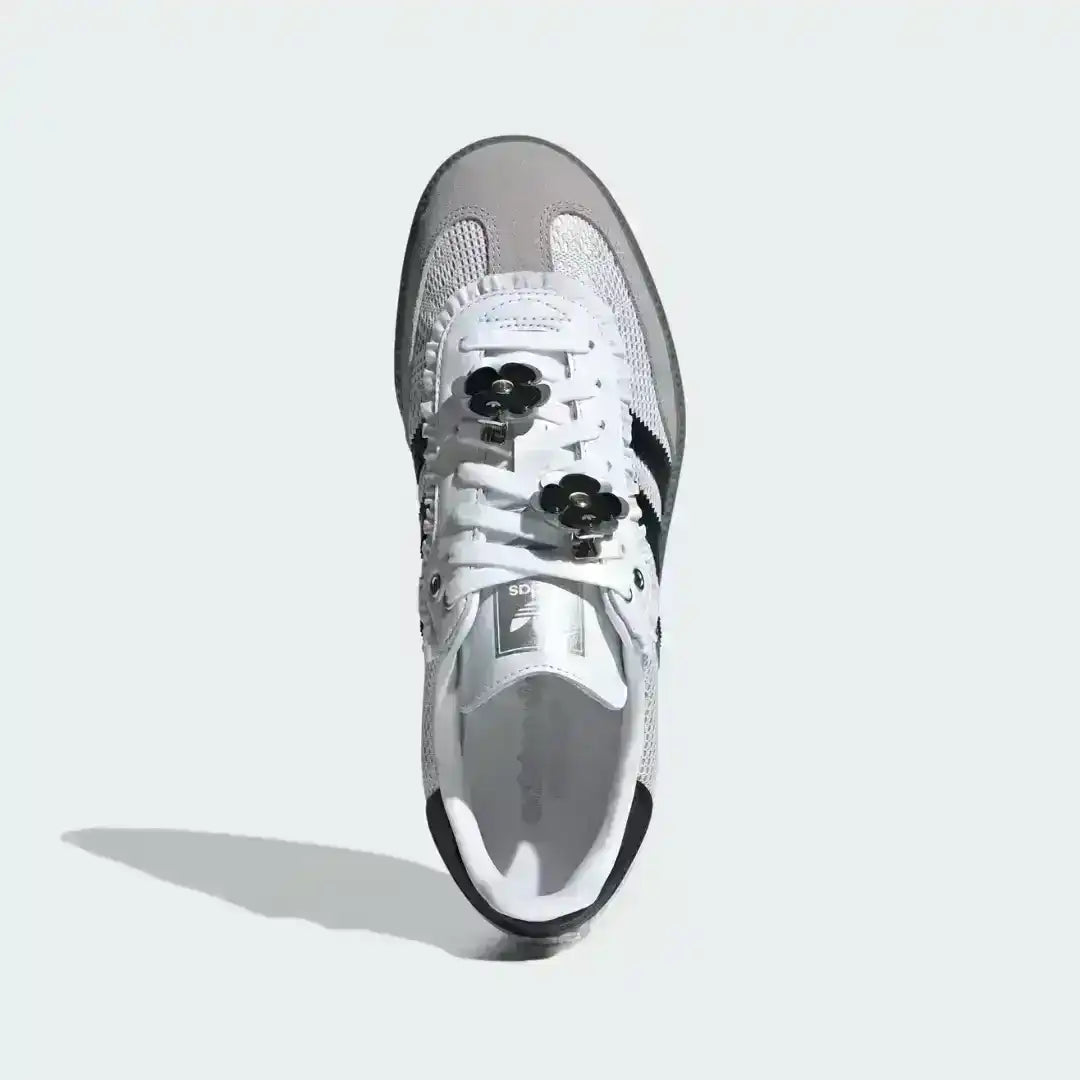 Stylish custom Adidas Samba OG sneakers in white with black accents, showcasing decorative black flower patches with gold centers and striped laces.