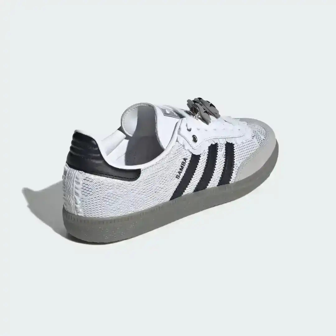 Detailed look at the custom flower patch accessories and black and white striped laces on a pair of classic white Adidas Samba OG trainers.