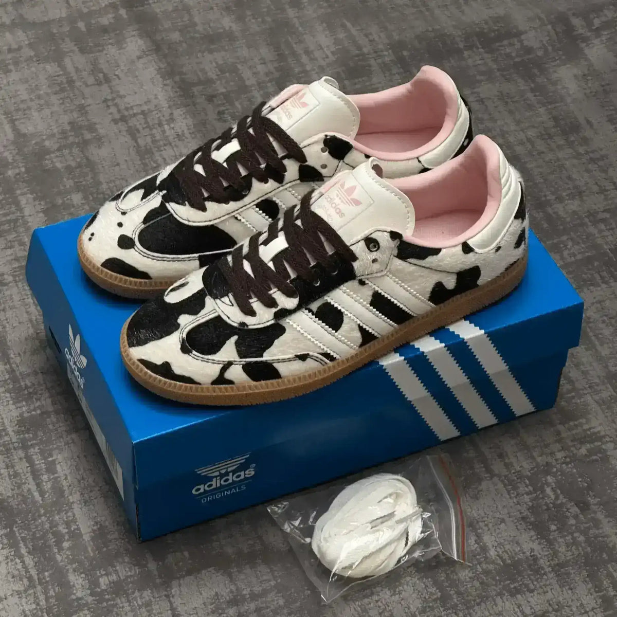Black and white cow-pattern low-top sneakers with pale soles.