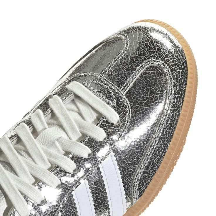 Silver-colored three-stripe low-top sneakers with gum soles.