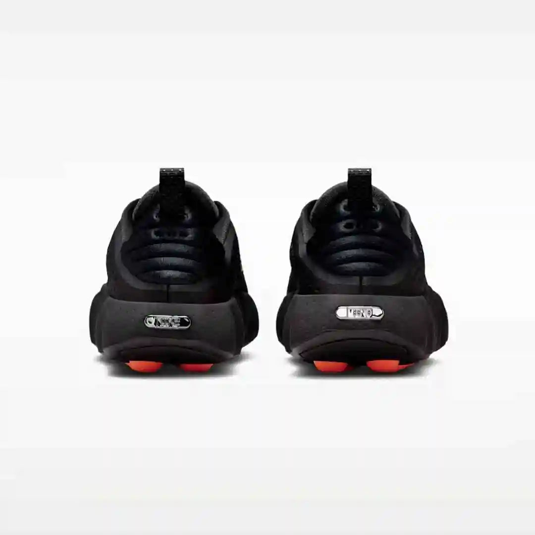 Black sneakers with orange sole pods, rear pair view.