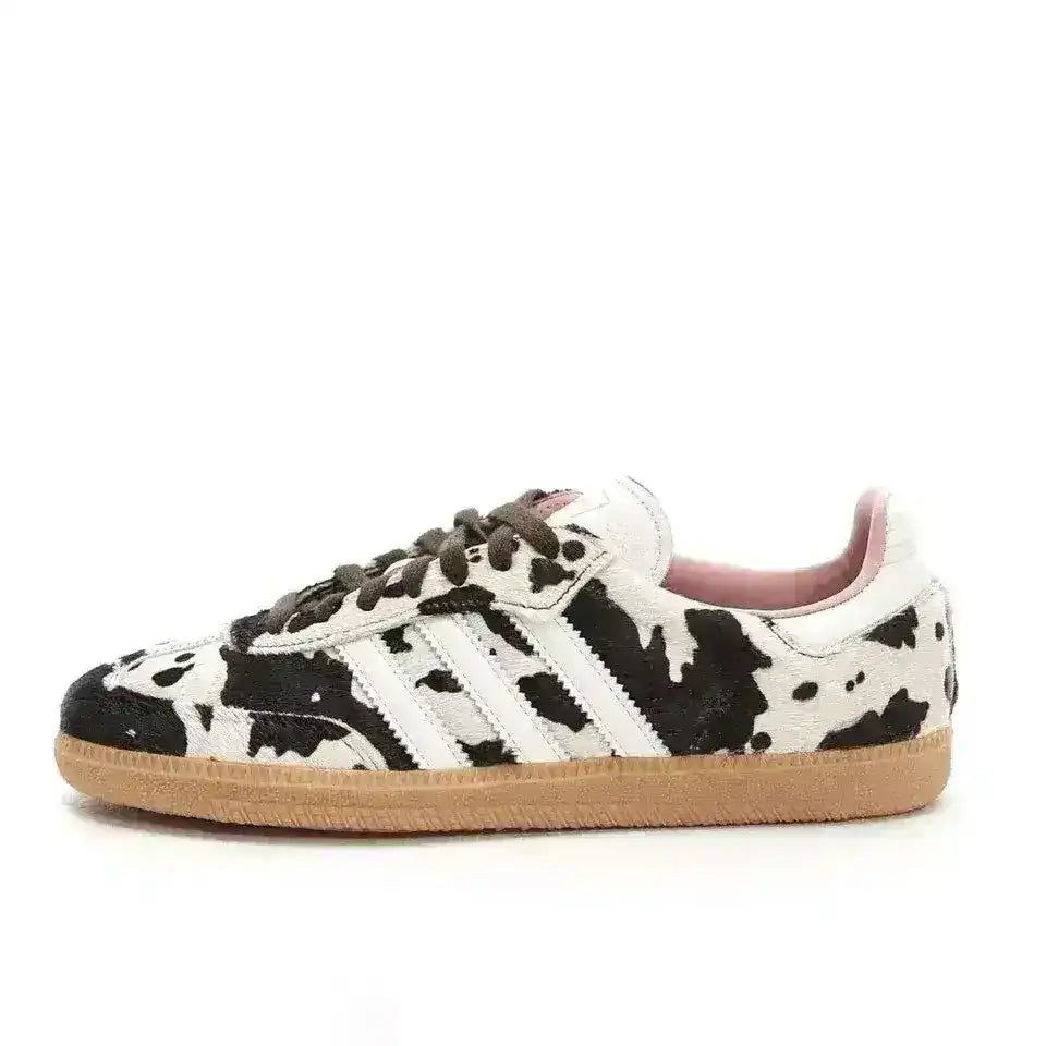 Black and white cow-pattern low-top sneakers with pale soles.