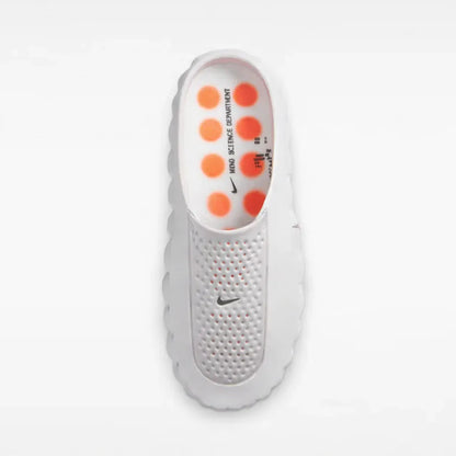 White backless footwear with a textured footbed and orange raised pods.