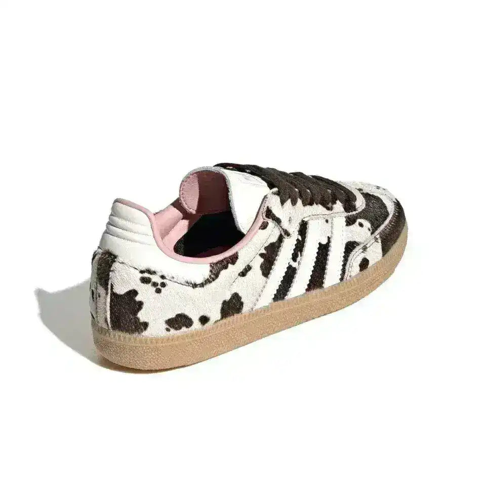 Black and white cow-pattern low-top sneakers with pale soles.