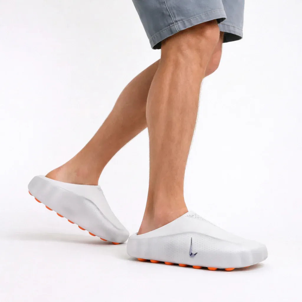 White backless footwear with a textured footbed and orange raised pods.