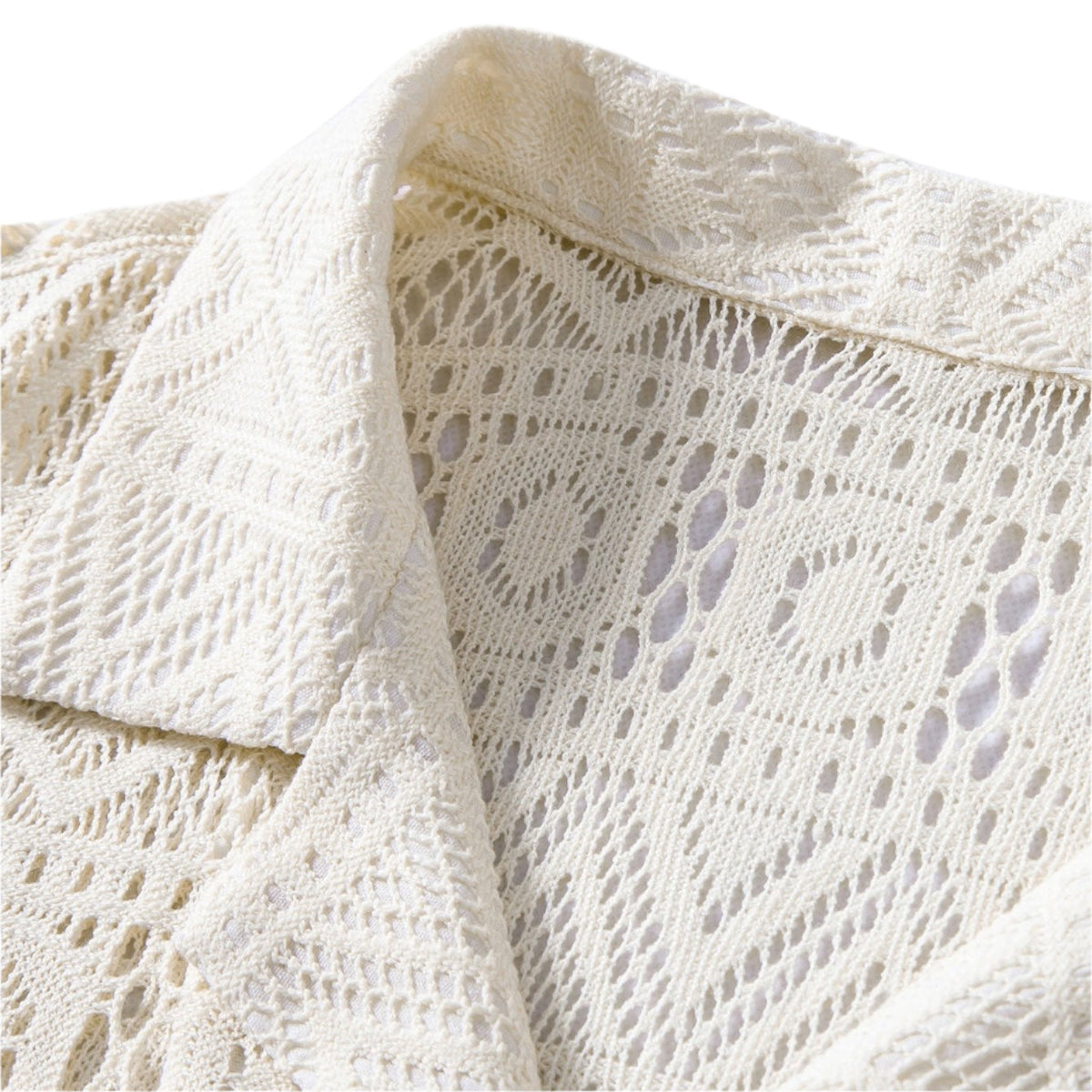 Close-up of a cream openwork shirt's collar, button and fabric.