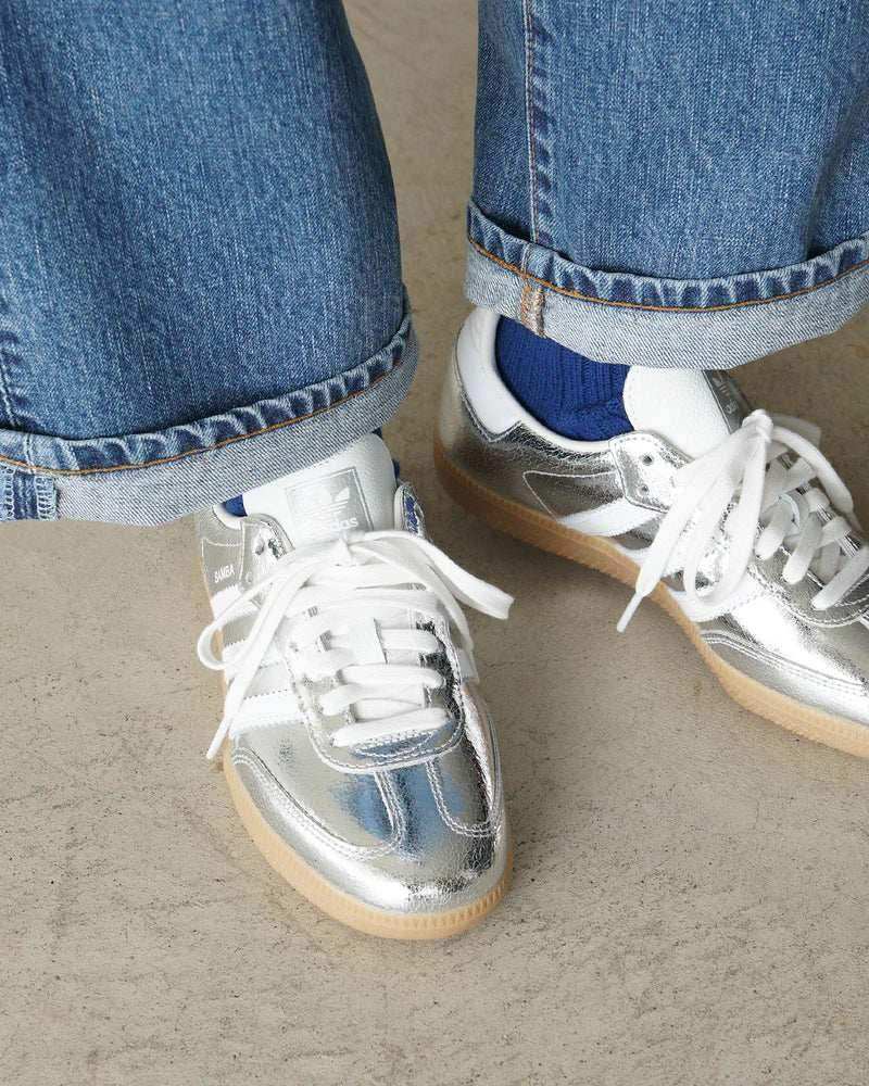 Silver-colored three-stripe low-top sneakers with gum soles.