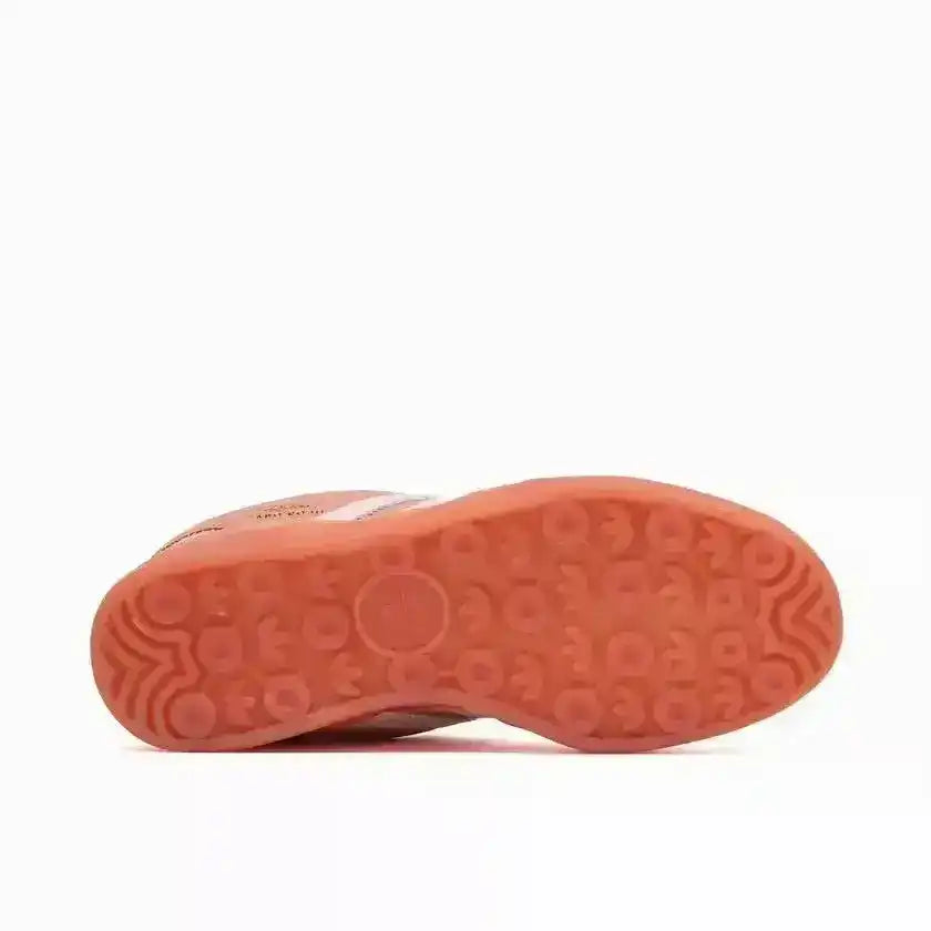 Coral-colored sneaker outsole with circular tread, bottom view.