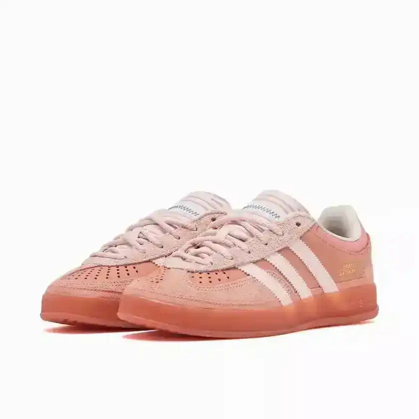 Coral pink three-stripe low-top sneakers with translucent-look soles.